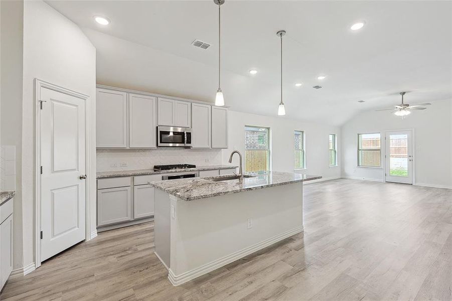 Kitchen featuring backsplash, light hardwood / wood-style flooring, sink, and plenty of natural light