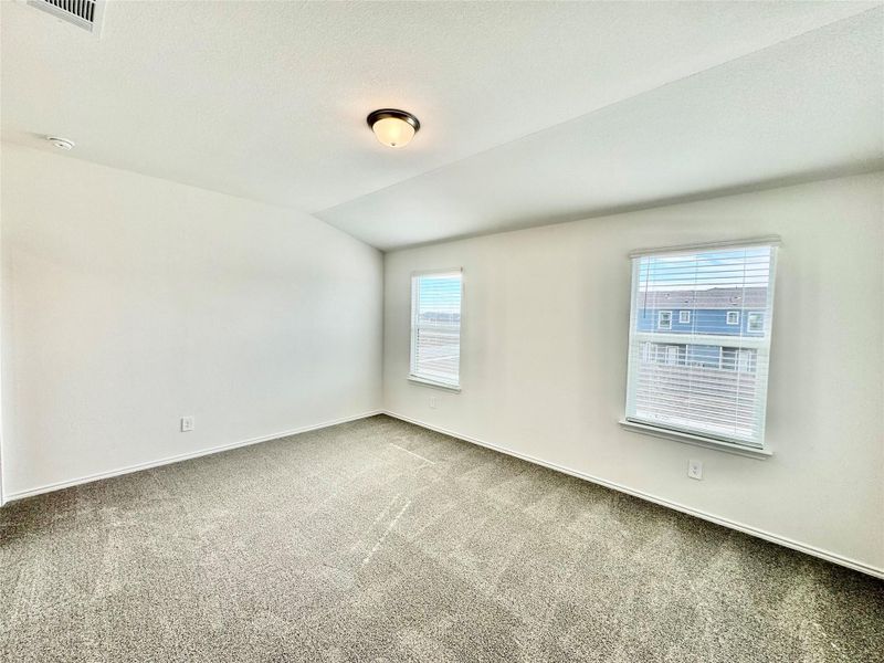 Empty room featuring carpet flooring, vaulted ceiling, and a textured ceiling