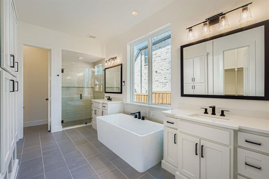 Full bathroom featuring a stall shower, a freestanding tub, two vanities, dark tile patterned flooring, and recessed lighting Full bathroom featuring a stall shower, a freestanding tub, two vanities, dark tile patterned flooring, and recessed lighting