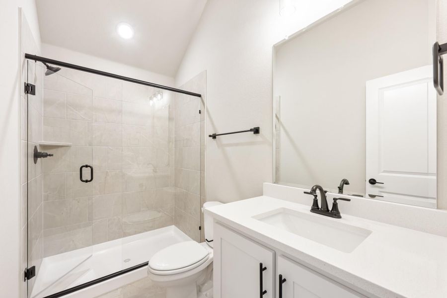 Bathroom with glass-door tile shower, white vanity, and black hardware fixtures