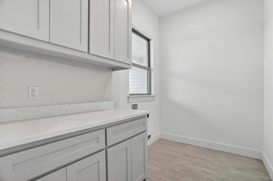 Utility room featuring light gray shaker cabinetry, a white countertop, and tiled flooring
