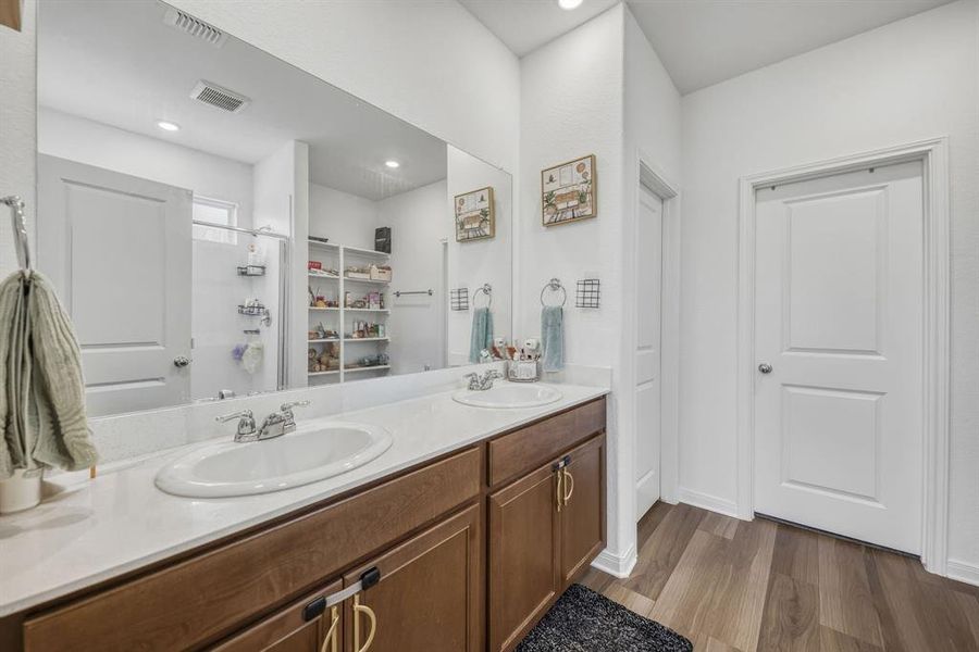 Dual vanity with undermount sinks, stone-finish countertop, and wood-tone cabinetry Dual vanity with undermount sinks, stone-finish countertop, and wood-tone cabinetry