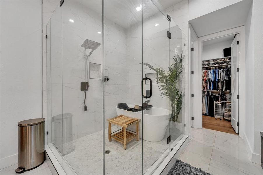 Bathroom featuring light marble finish flooring, a freestanding bath, a walk in closet, and a marble finish shower Bathroom featuring light marble finish flooring, a freestanding bath, a walk in closet, and a marble finish shower