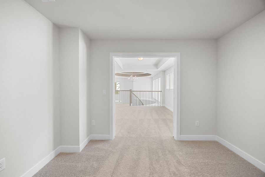 Corridor featuring light colored carpet and a chandelier