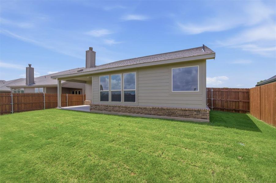 Expansive backyard featuring a manicured lawn, full privacy fencing, and a concrete patio