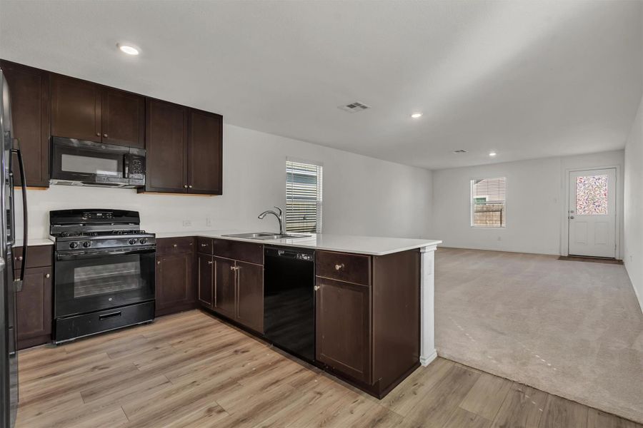 Rich wood cabinetry and crisp countertops anchor this functional open-concept layout. Rich wood cabinetry and crisp countertops anchor this functional open-concept layout.
