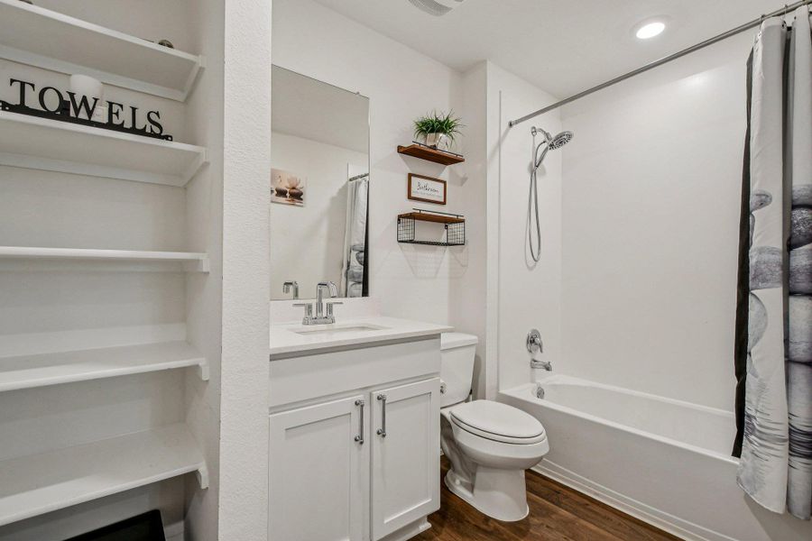 Bathroom featuring vanity, dark wood-type flooring, shower / bath combo, built in features, and a closet
