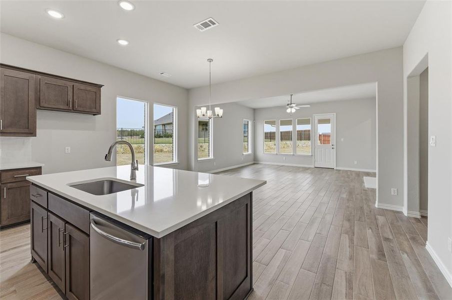 Kitchen with dark wood finish cabinets, hanging lights, stainless steel dishwasher, light wood finished floors, and a ceiling fan