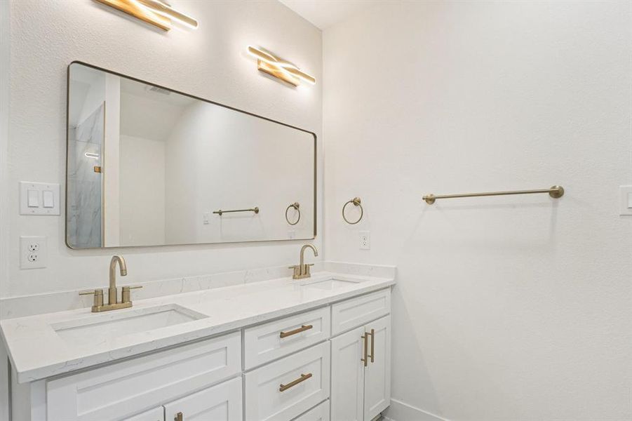 Bathroom featuring double vanity and baseboards Bathroom featuring double vanity and baseboards