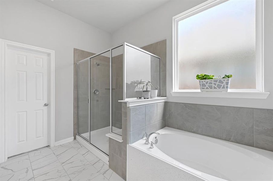 The ensuite bathroom features a walk-in shower with glass doors, a separate deep soaking bathtub, and a large walk in closet.