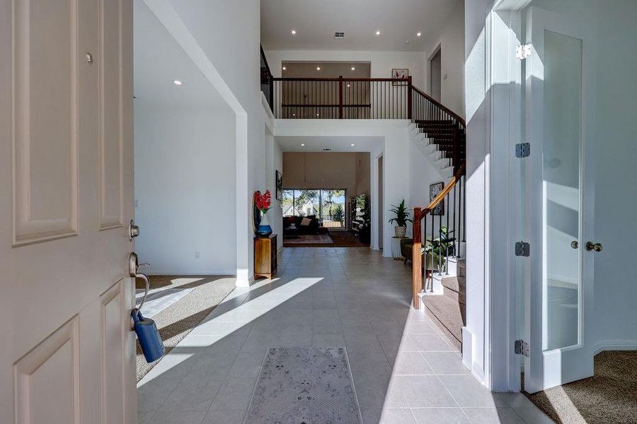 Foyer with stairs, a high ceiling, recessed lighting, and light tile patterned flooring