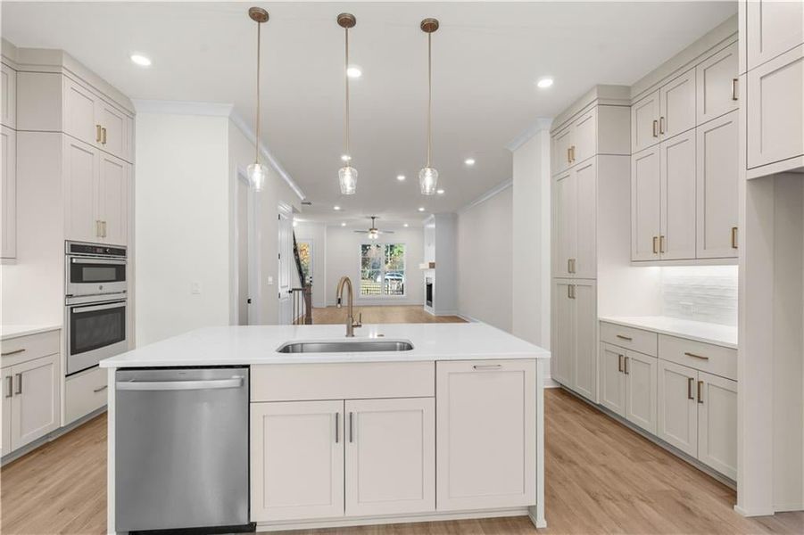 Kitchen featuring light wood-style flooring, appliances with stainless steel finishes, pendant lighting, a ceiling fan, and open floor plan