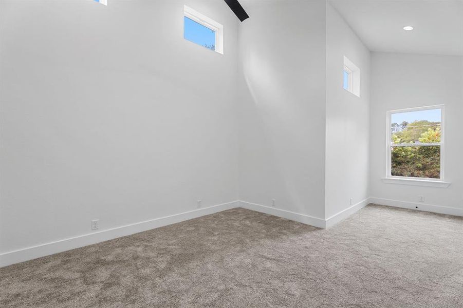 Unfurnished room with high vaulted ceiling and carpet floors Unfurnished room with high vaulted ceiling and carpet floors