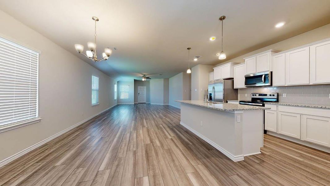 Open-concept living area featuring wood-finish flooring, a contemporary chandelier, and recessed lighting