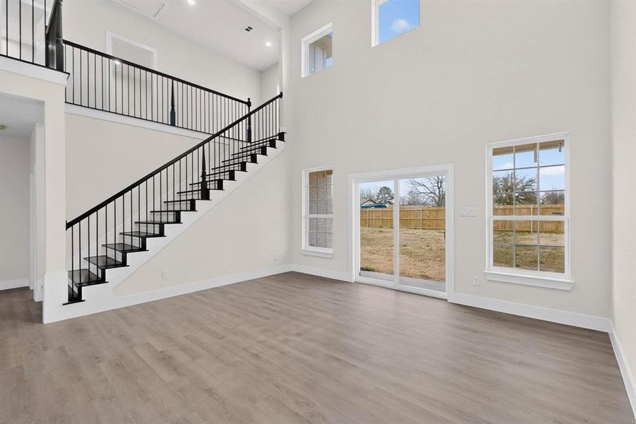 Living room with light wood-style floors, a high ceiling, and recessed lighting Living room with light wood-style floors, a high ceiling, and recessed lighting