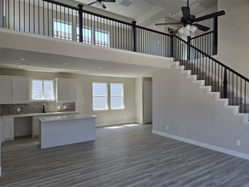 Kitchen featuring white cabinets, open floor plan, a towering ceiling, a kitchen island, and dark wood-style floors