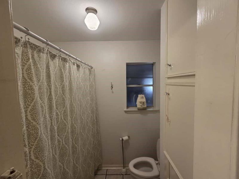 Bathroom with a shower with curtain and light tile patterned floors Bathroom with a shower with curtain and light tile patterned floors