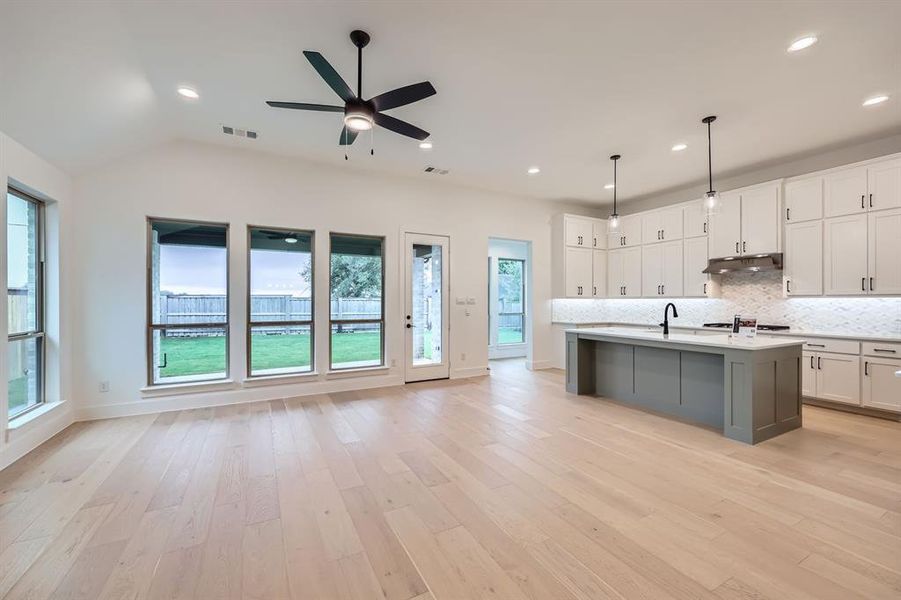 Kitchen featuring a kitchen island with sink, a healthy amount of sunlight, pendant lighting, and light hardwood / wood-style flooring