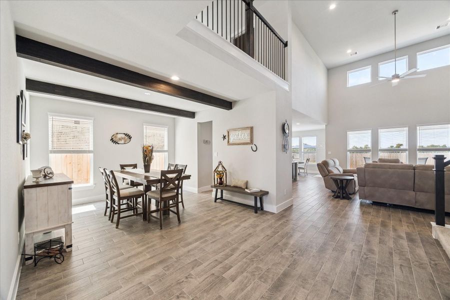Open-concept dining and living area with tile flooring, exposed beams, and soaring ceilings filled with natural light. Open-concept dining and living area with tile flooring, exposed beams, and soaring ceilings filled with natural light.