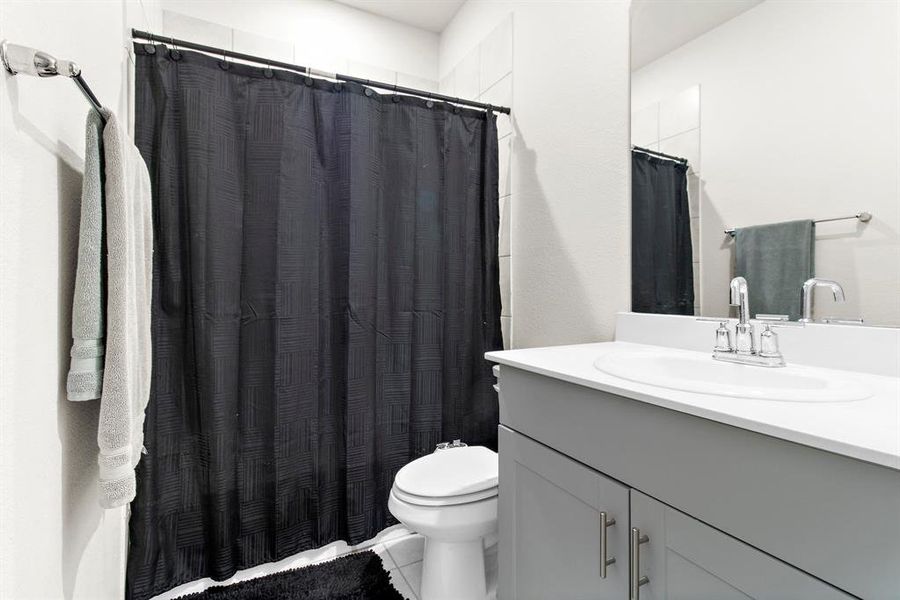 Bathroom featuring vanity, curtained shower, and tile patterned flooring Bathroom featuring vanity, curtained shower, and tile patterned flooring