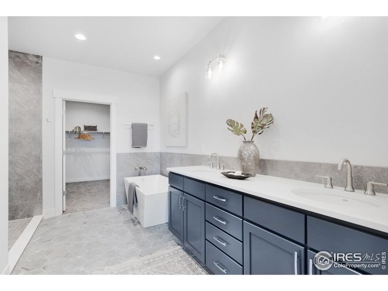 The primary ensuite, featuring dual vanities, a full-width mirror, Quartz counters, porcelain tile flooring, and porcelain vanity sinks