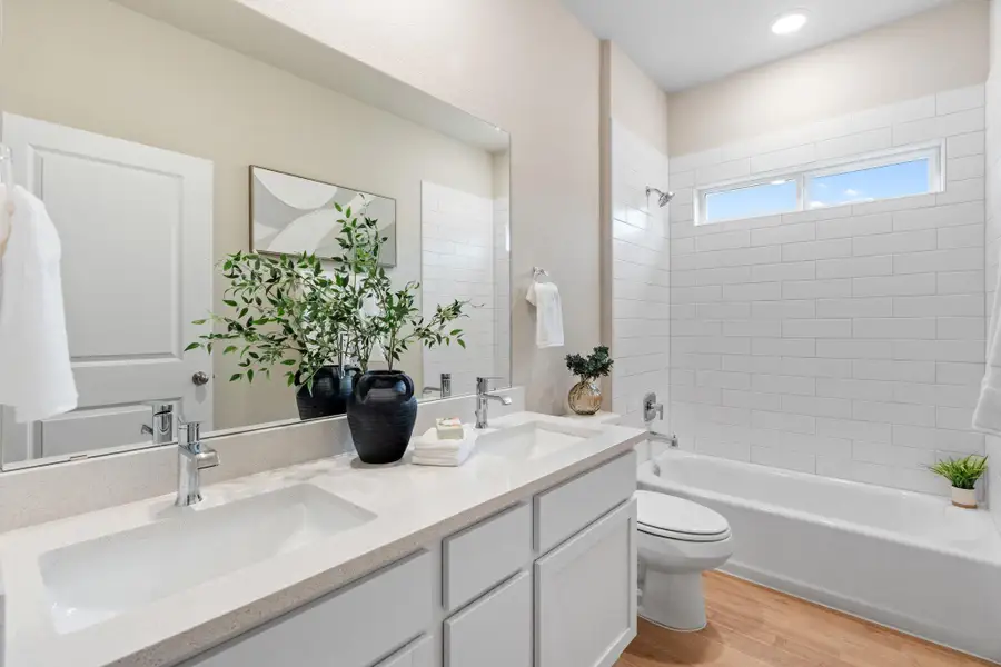 Full bathroom featuring bathing tub / shower combination, light wood finished floors, and double vanity Full bathroom featuring bathing tub / shower combination, light wood finished floors, and double vanity