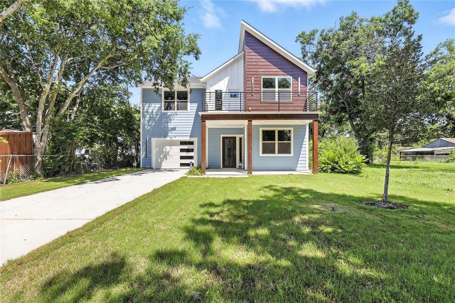 Contemporary house with a balcony, an attached garage, concrete driveway, and board and batten siding