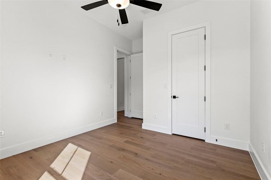 Unfurnished bedroom with wood finished floors and ceiling fan Unfurnished bedroom with wood finished floors and ceiling fan