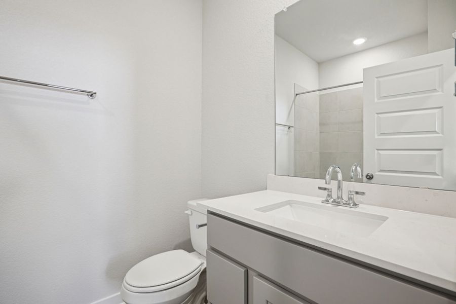 A bathroom with a sink toilet and mirror.