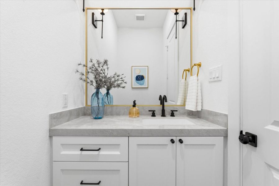 Convenient half bathroom located on the main floor, featuring a stylish vanity and dual wall sconces