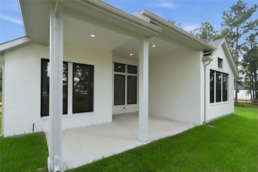 This expansive covered patio provides a fantastic outdoor living space, perfect for relaxing or entertaining year-round. The generous concrete area is supported by sturdy columns, and a wall of large windows and glass doors creates a seamless indoor-outdoor connection. This expansive covered patio provides a fantastic outdoor living space, perfect for relaxing or entertaining year-round. The generous concrete area is supported by sturdy columns, and a wall of large windows and glass doors creates a seamless indoor-outdoor connection.