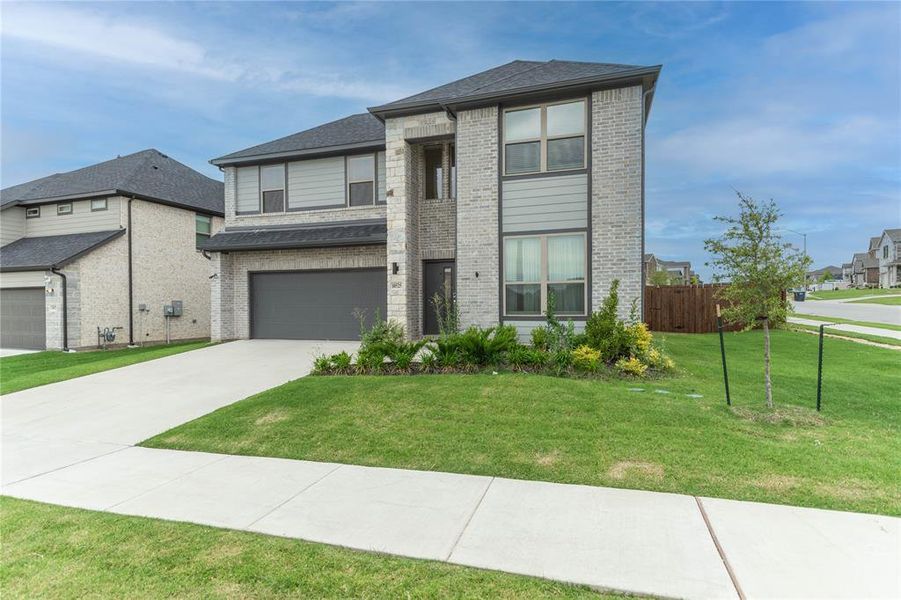 View of front of house with brick siding, driveway, a garage, and roof with shingles