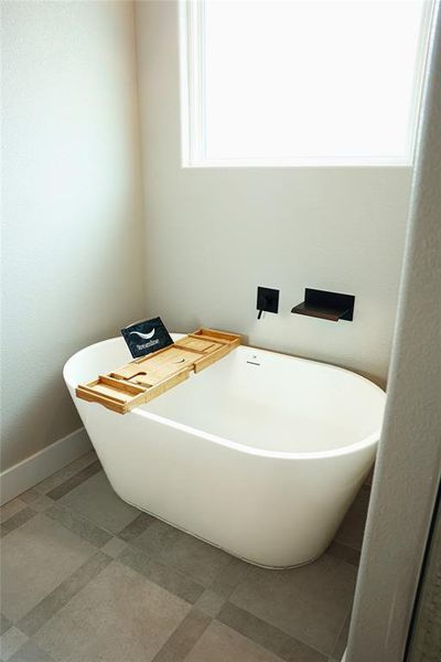 Freestanding soaking tub with wall-mounted matte black fixtures