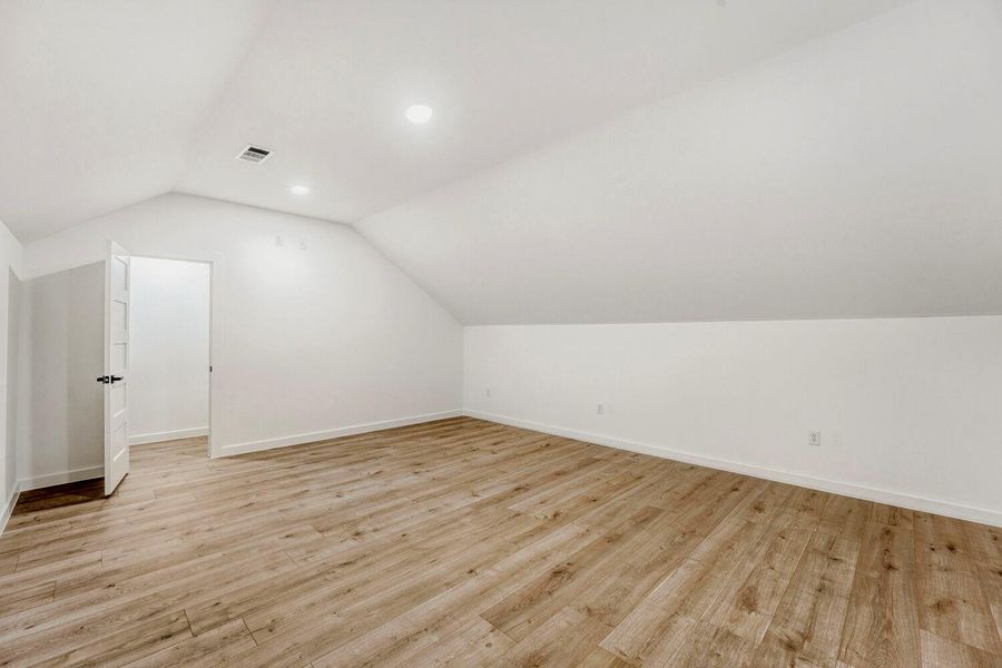 Bonus room with light wood finished floors and recessed lighting