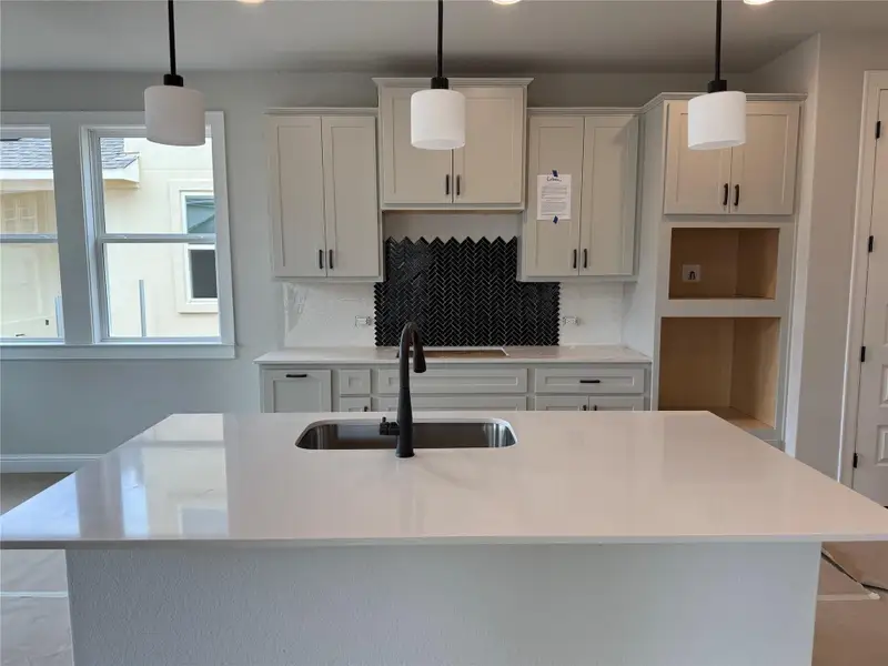 Kitchen featuring tasteful backsplash, a kitchen island with sink, recessed lighting, and light countertops Kitchen featuring tasteful backsplash, a kitchen island with sink, recessed lighting, and light countertops
