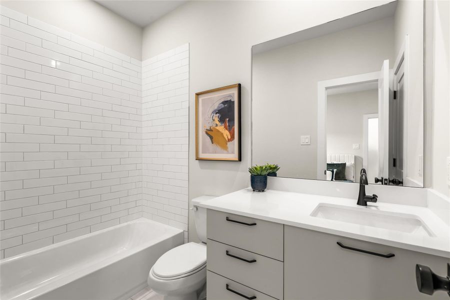 The first-floor full bath pairs a tub/shower combination with an extended vanity, undermount sink, and practical cabinetry for storage.