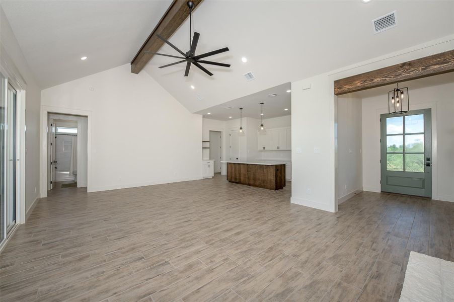 Unfurnished living room with beam ceiling, a ceiling fan, plenty of natural light, wood finish floors, and recessed lighting
