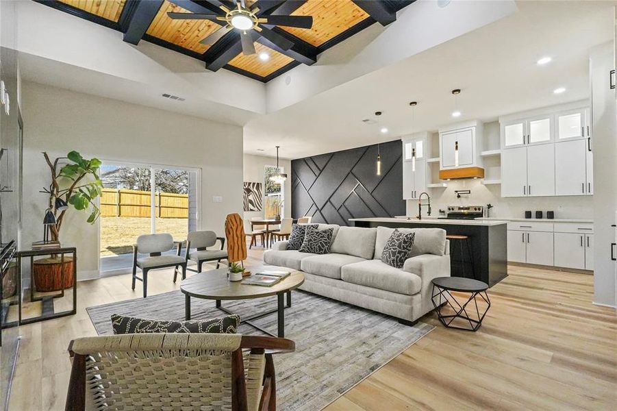Living room with a wooden ceiling with exposed beams, light wood finished floors, recessed lighting, and ceiling fan