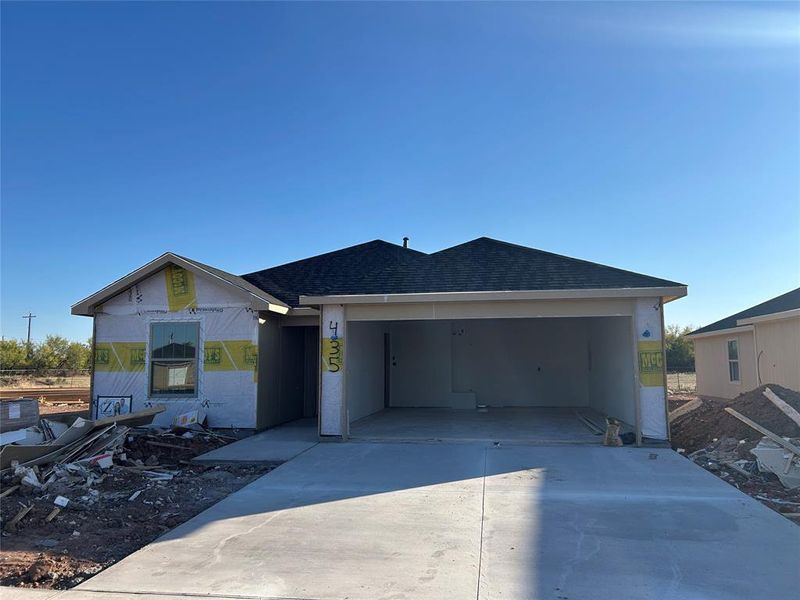 Property in mid-construction featuring a shingled roof, driveway, and an attached garage Property in mid-construction featuring a shingled roof, driveway, and an attached garage