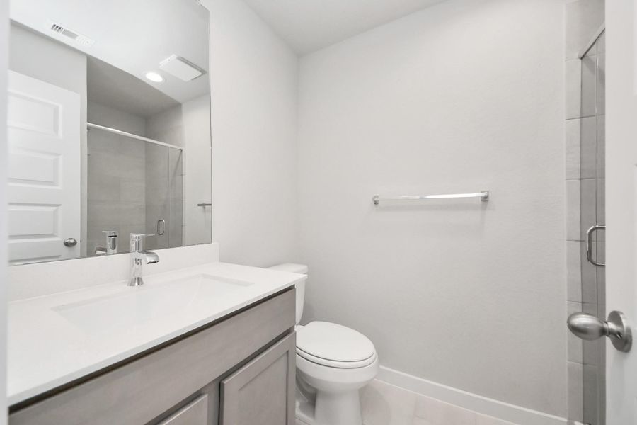 Secondary bath features tile flooring, bath/shower combo with tile surround, light stained wood cabinets, beautiful light countertop. Sample photo of completed home with similar floor plan. Actual colors and selections may vary.