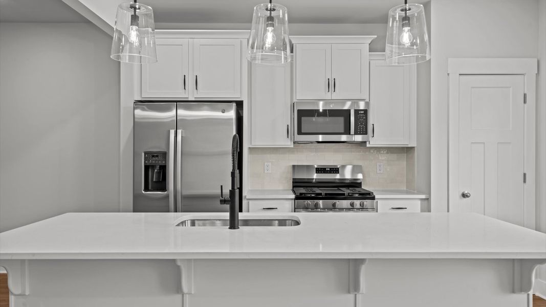 Exclusive DRB Homes kitchen with a 9-foot island, elevated finishes, and pendant lighting in a prime location Exclusive DRB Homes kitchen with a 9-foot island, elevated finishes, and pendant lighting in a prime location