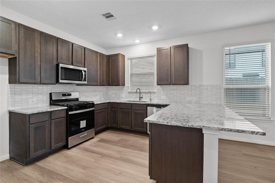 This kitchen is by far any chef’s dream! This spacious kitchen features high ceilings, stained cabinets, granite countertops, SS appliances, modern tile backsplash, recessed lighting, extended counter space for breakfast bar, and a walk-in pantry all overlooking your huge family room.