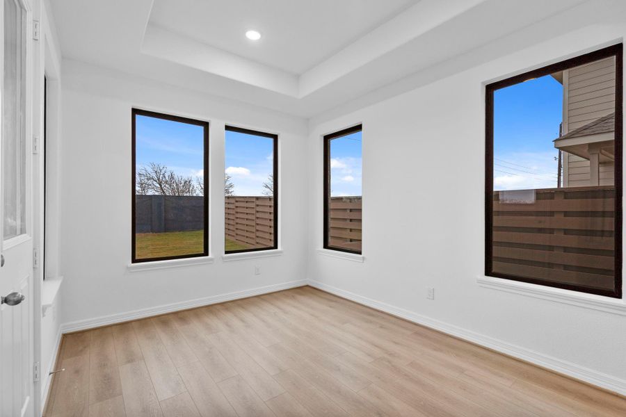 The dining room is encompassed with light due to the architectural bronze window frames, and highlighted with a refined tray ceiling.