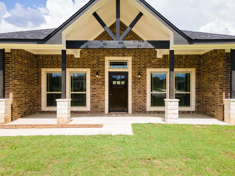 View of exterior entry with brick veneer and a yard View of exterior entry with brick veneer and a yard