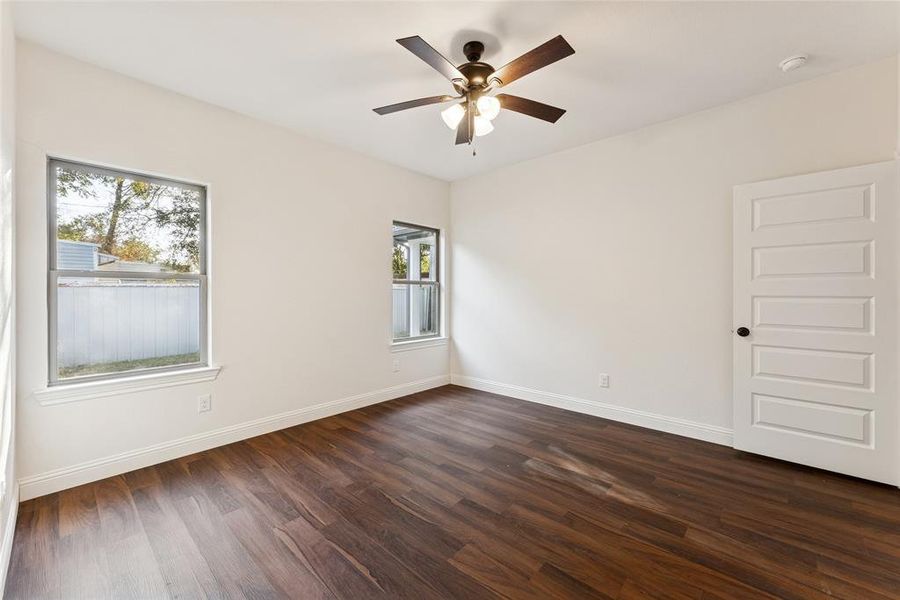 Unfurnished room with dark wood finished floors and ceiling fan