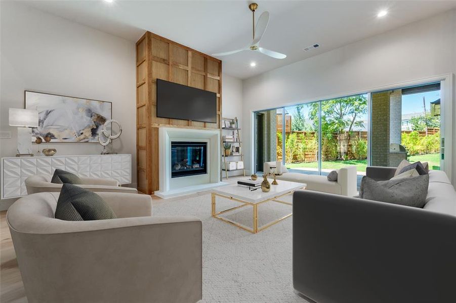 Living room with a glass covered fireplace, recessed lighting, wood finished floors, and ceiling fan Living room with a glass covered fireplace, recessed lighting, wood finished floors, and ceiling fan