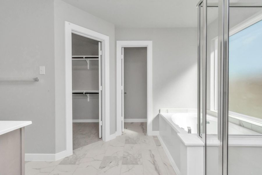 Extra glimpse into the primary bathroom featuring a spacious walk-in closet, adding an extra touch of convenience and luxury to your daily routine. Sample photo of completed plan. As-built color and selections may vary. Extra glimpse into the primary bathroom featuring a spacious walk-in closet, adding an extra touch of convenience and luxury to your daily routine. Sample photo of completed plan. As-built color and selections may vary.