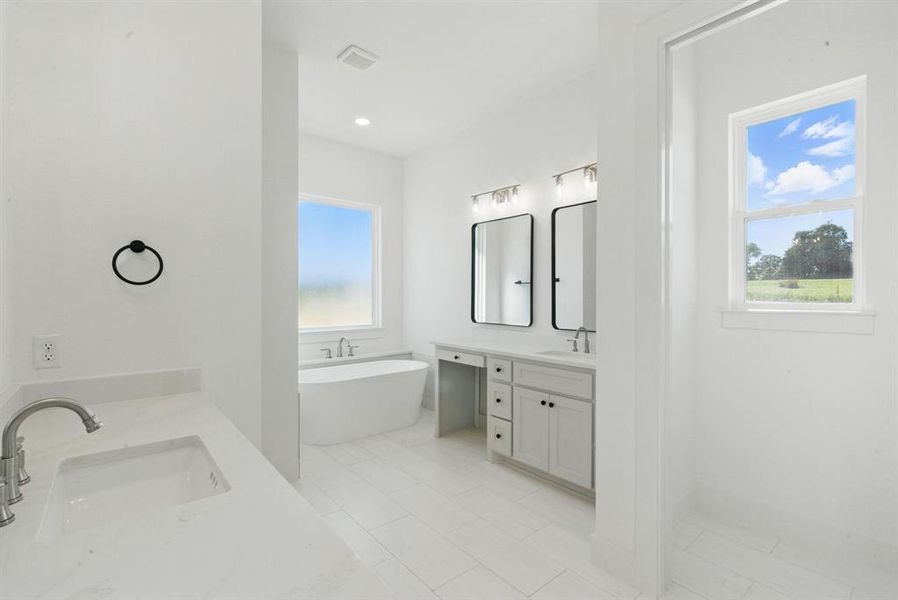 Bathroom with a soaking tub, two vanities, and light tile patterned floors Bathroom with a soaking tub, two vanities, and light tile patterned floors
