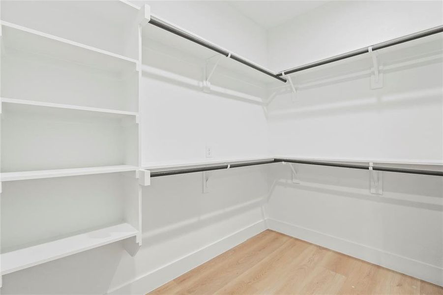 Spacious closet with light wood-type flooring Spacious closet with light wood-type flooring