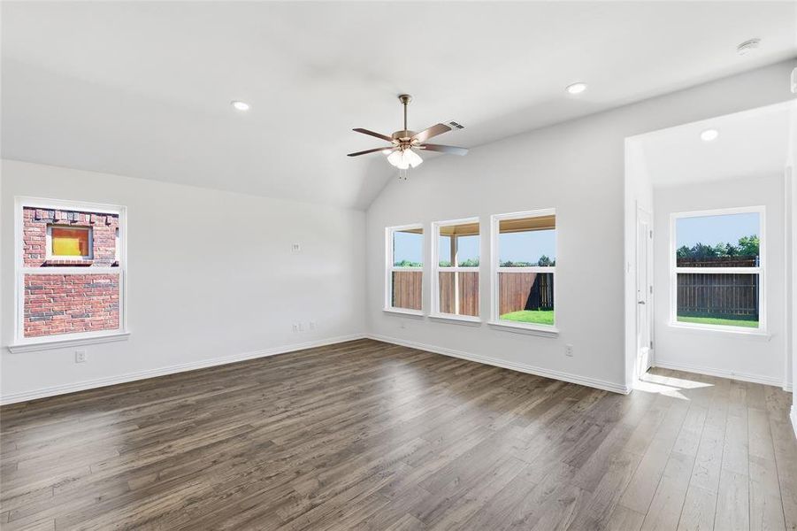 Spacious living area featuring wood-finish flooring, a vaulted ceiling, and recessed lighting